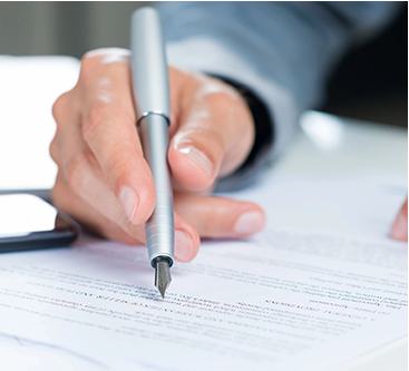 A person signing a document with a pen.