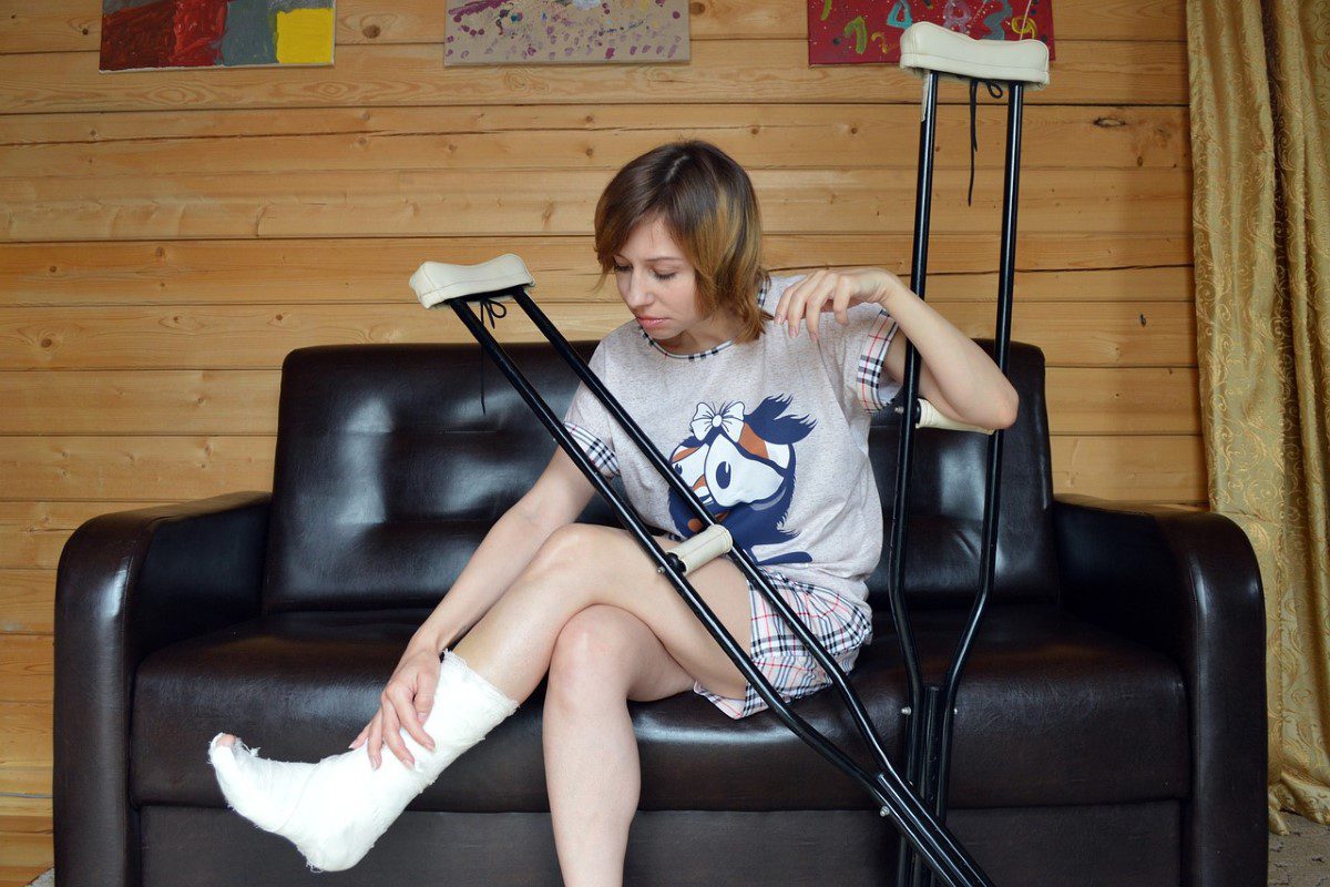 A woman sitting on the couch with crutches