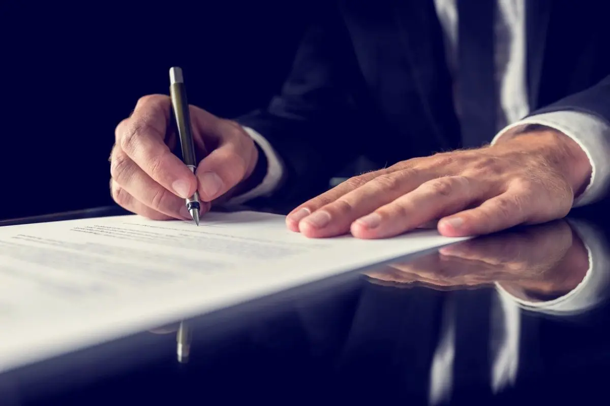 A man signing a document with a pen.