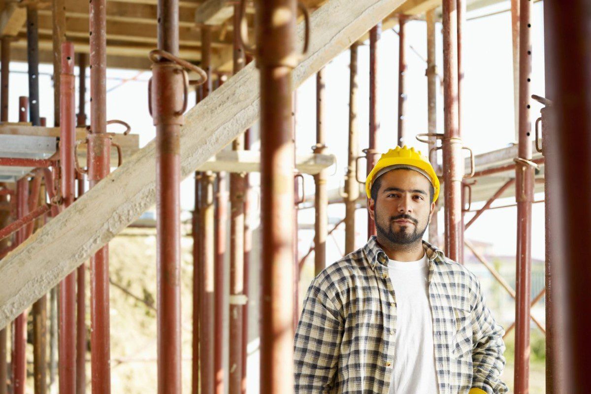 A man in plaid shirt and yellow hard hat.