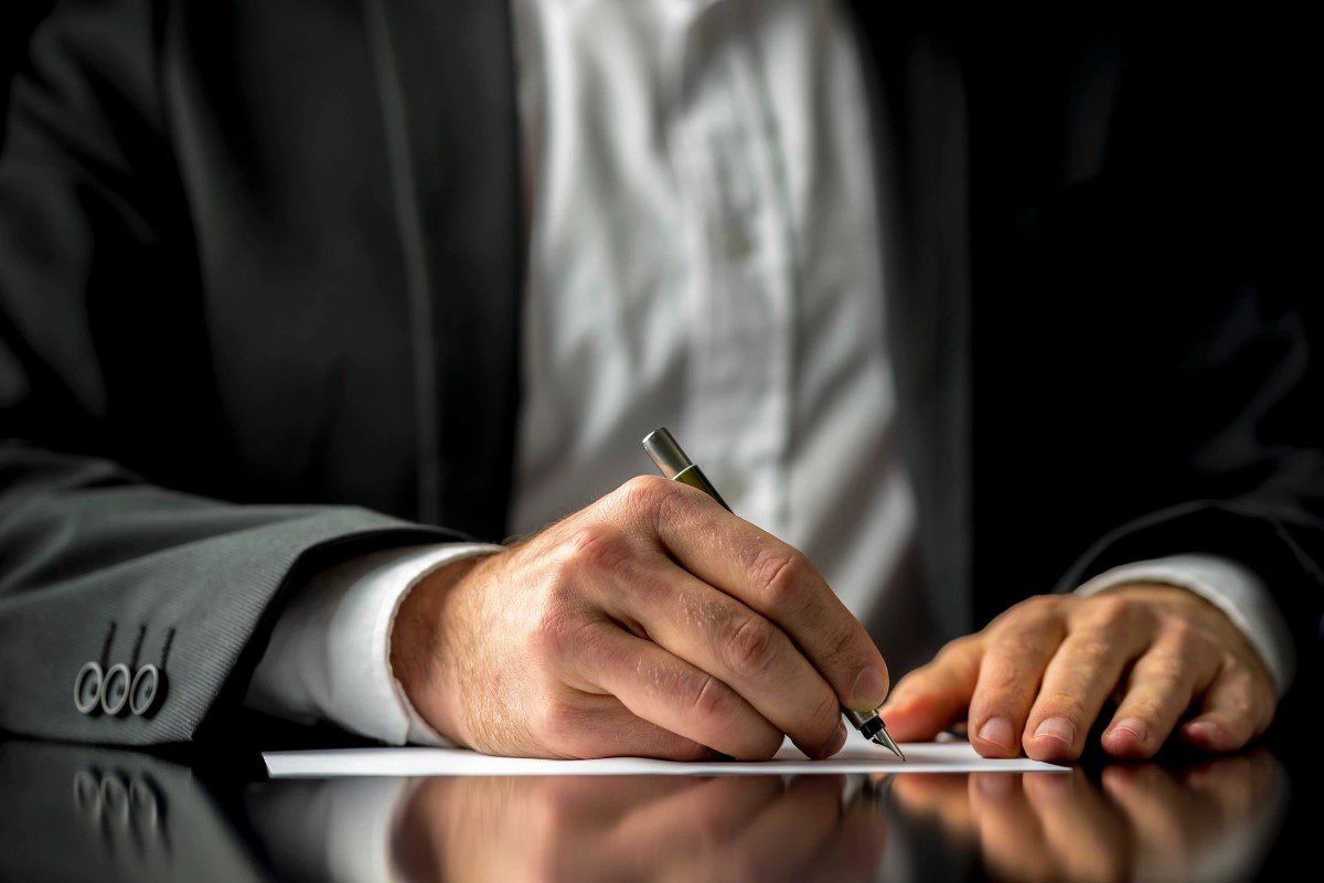 A businessman signing a document with a pen.
