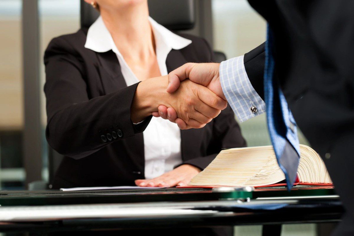 A businessman shaking hands with a woman at a desk.