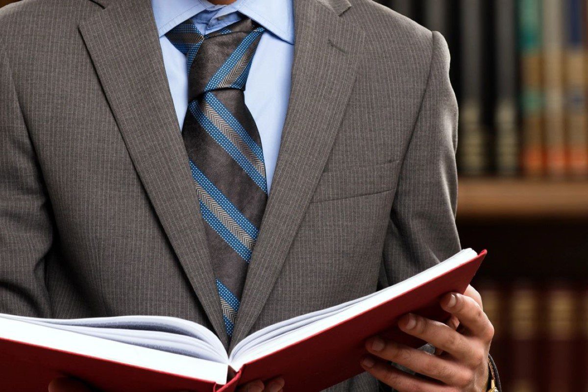 A man in a suit holding a book.