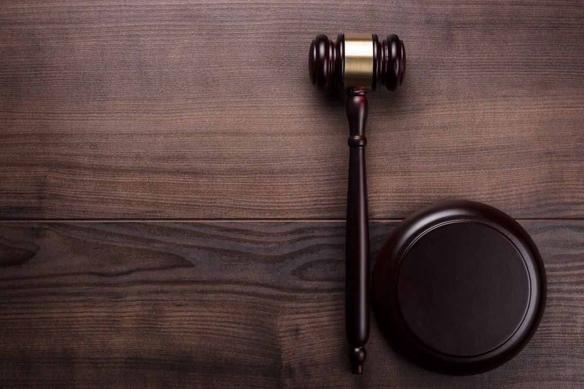 A wooden judge 's gavel and a round object on top of a table.