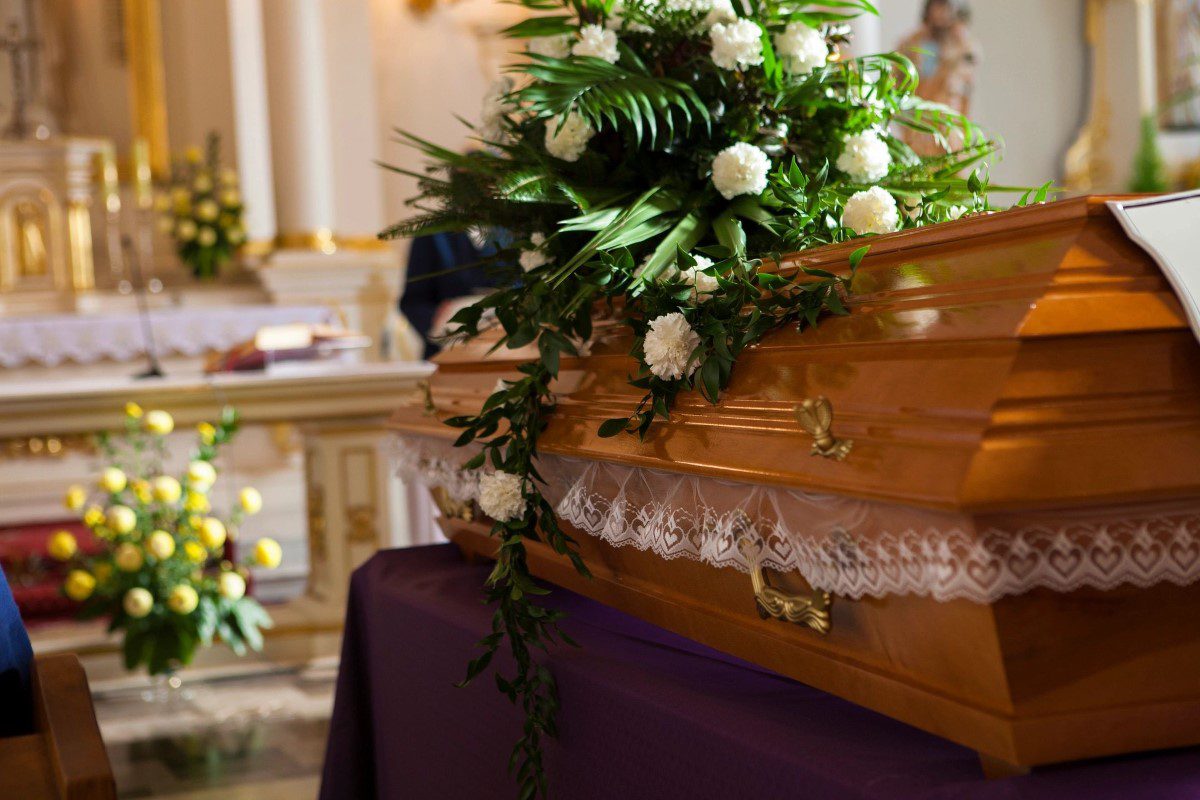 A wooden casket with flowers on top of it.