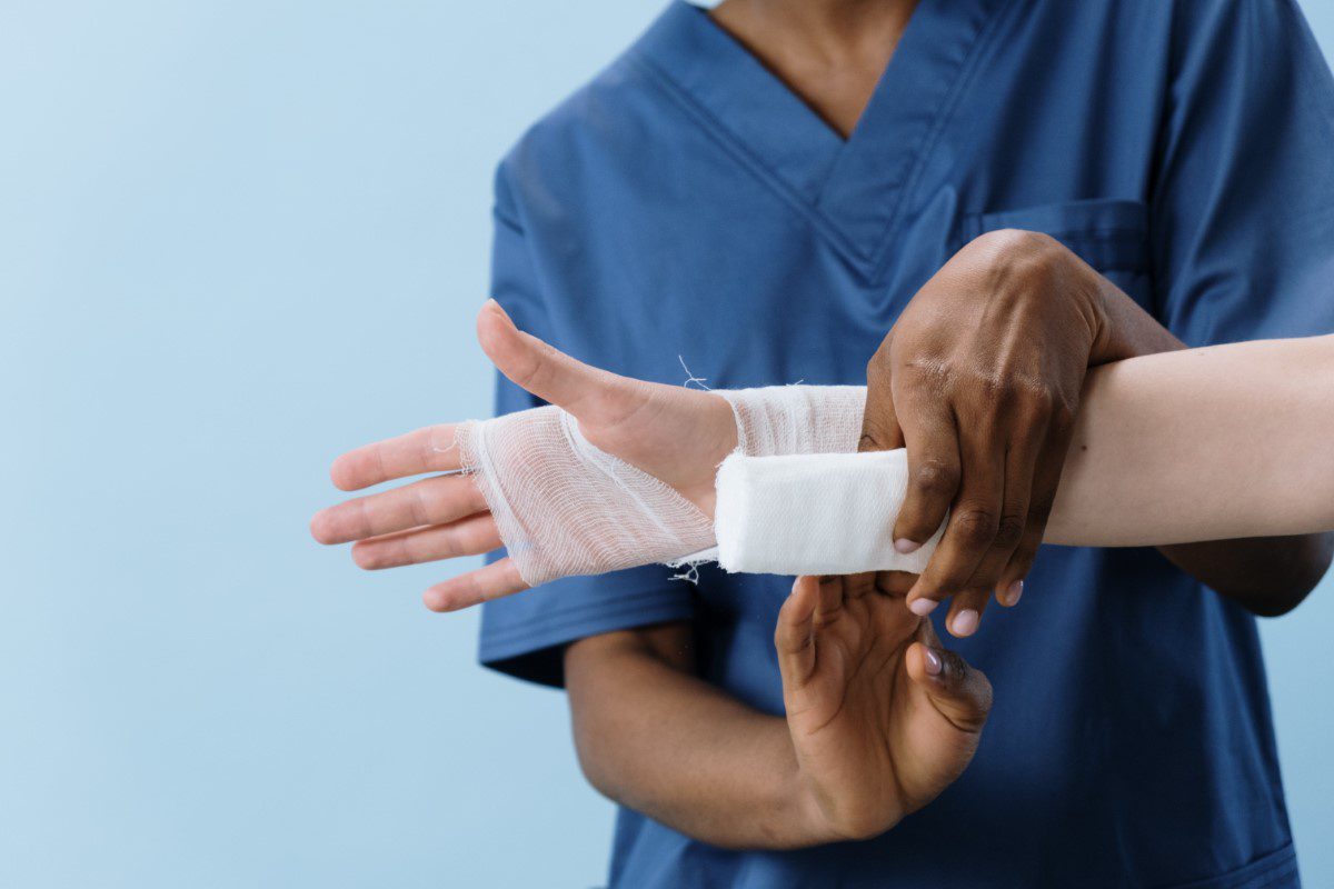 A nurse putting a bandage on a patient's hand.