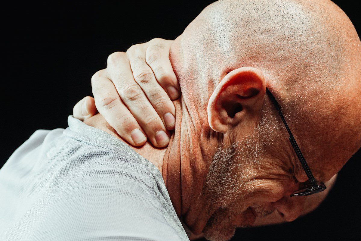 A bald man with a pain in his neck.