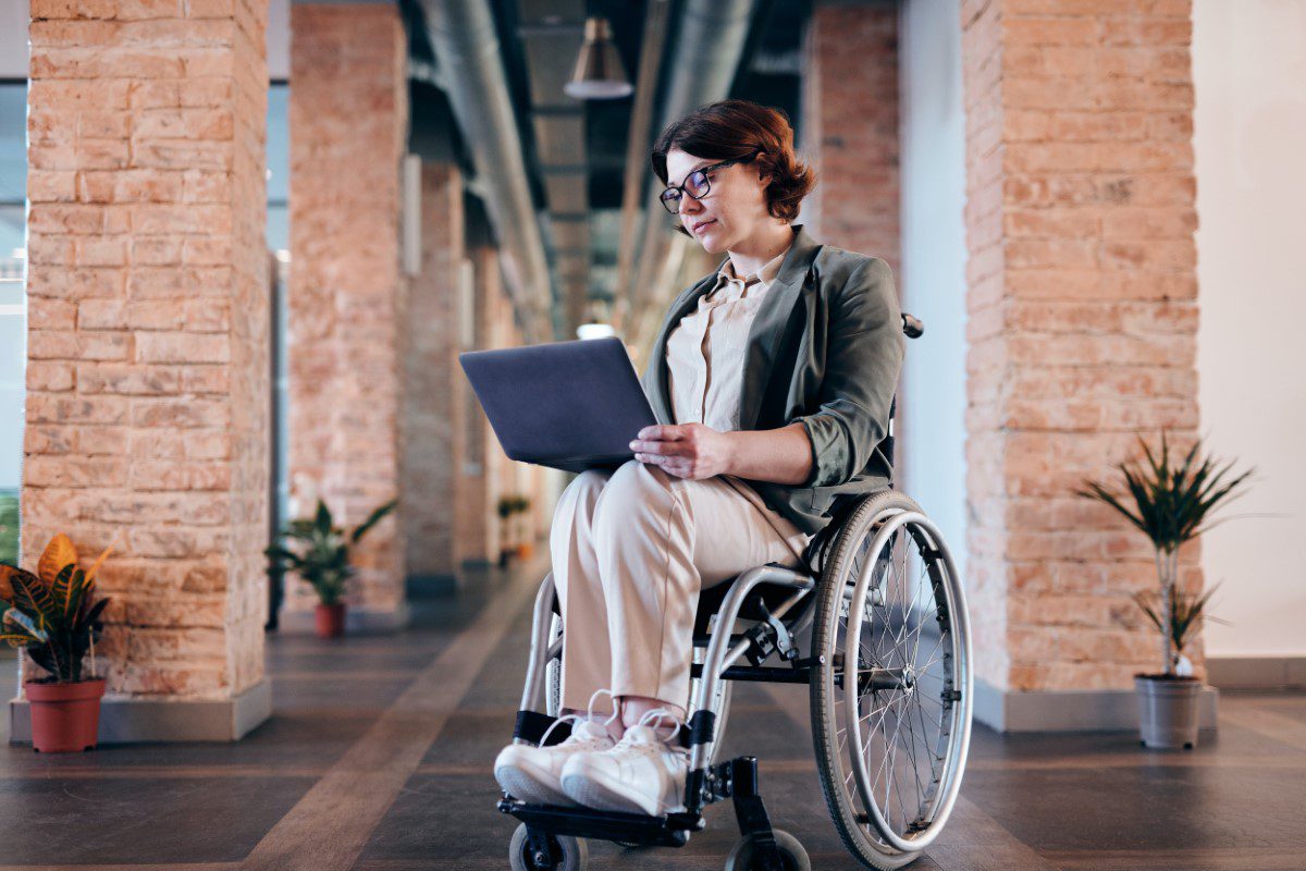 A woman in a wheelchair using a laptop.