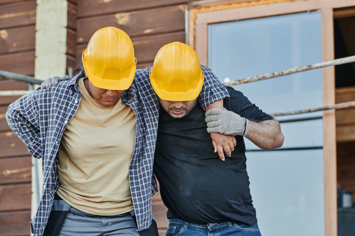 Two construction workers wearing hard hats standing in front of a house.