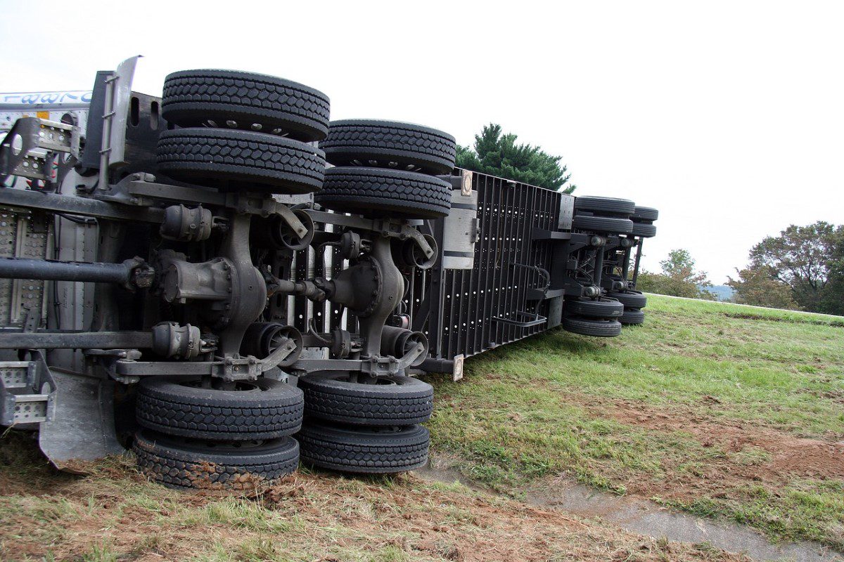 A truck that has been overturned on the side of the road.