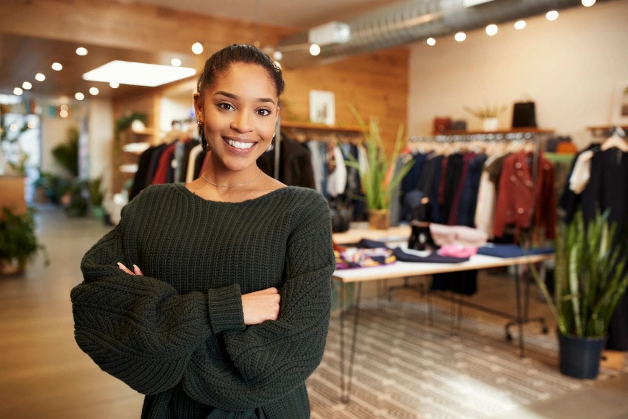 Young Hispanic woman smiling to camera in a clothes shop